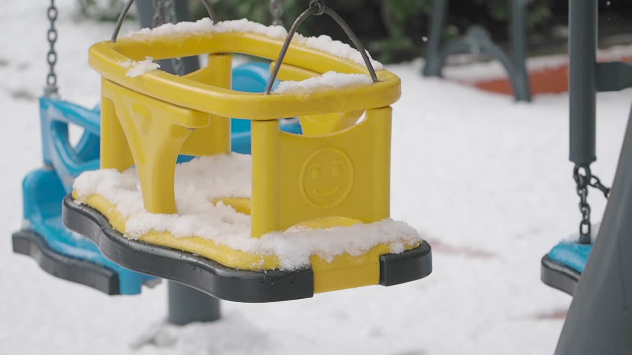 Yellow child swing covered in snow