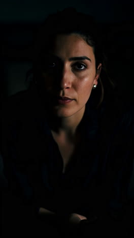 A woman in a dark setting, showing various emotional states