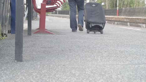 passenger wheels suitcase on train platform wide shot