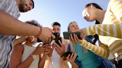 group of young friends using smartphones outdoors, enjoying social media together