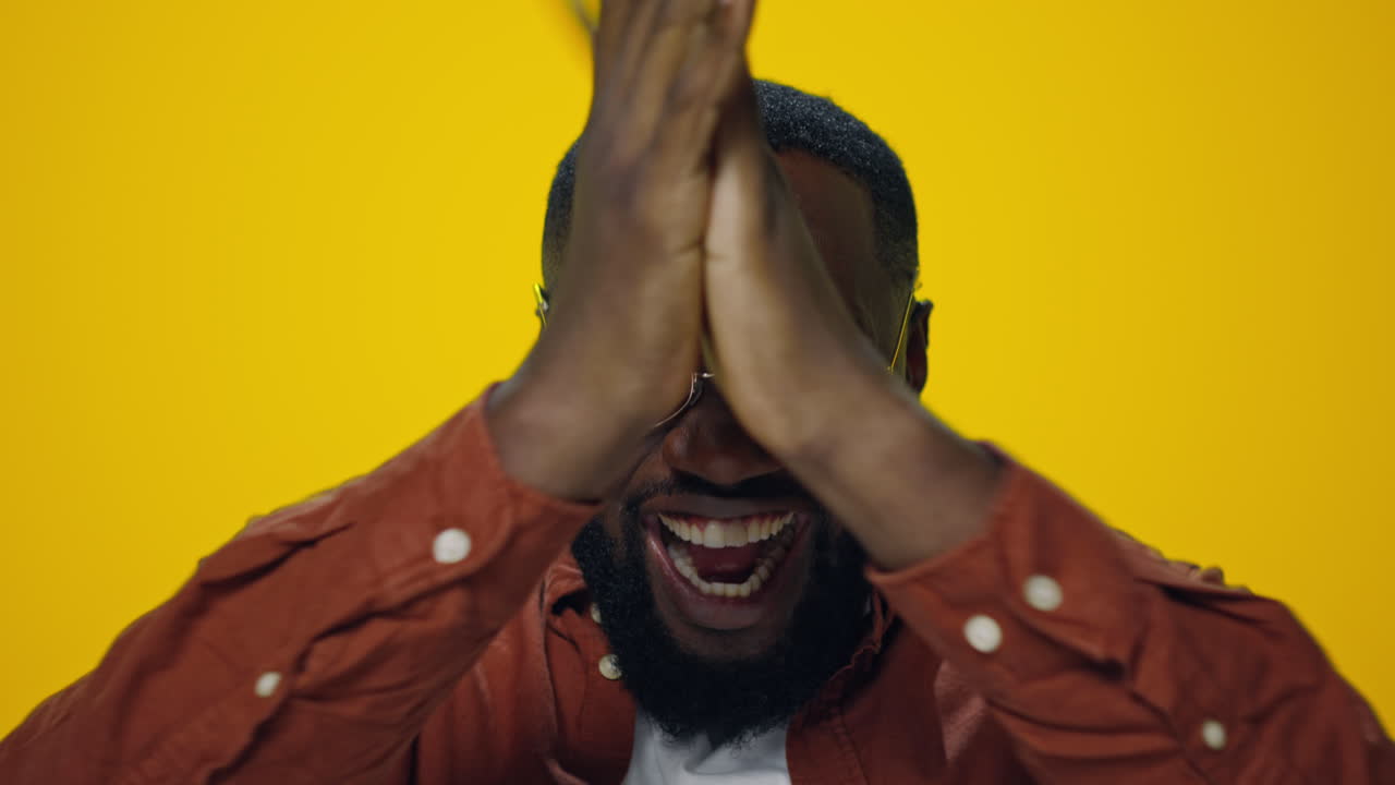 Portrait of happy african man celebrating victory on yellow background.