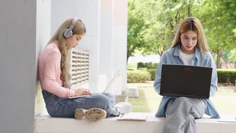 two asian girls student partners are working on a laptop help study together