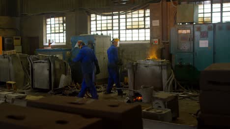 group of workers heating molten metal in workshop 4k