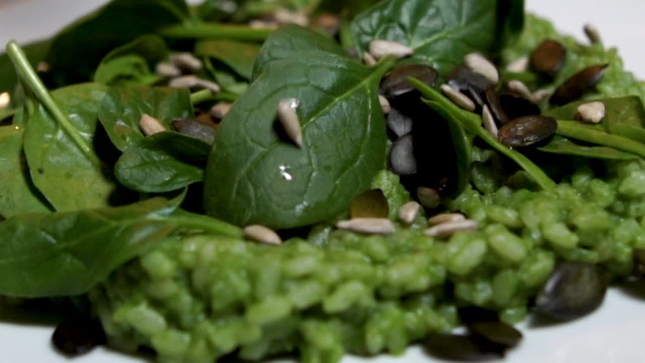Garnishing green spinach risotto with sunflower and pumpkin seeds, STILL, SLOMO