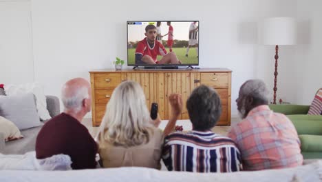 Video-Von-Verschiedenen-älteren-Freunden,-Die-Auf-Dem-Sofa-Sitzen-Und-Zu-Hause-Fußball-Schauen