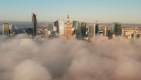 Downtown-high-rise-buildings-above-dense-fog.-Descending-footage-gradually-limiting-visibility-of-town.-Warsaw,-Poland
