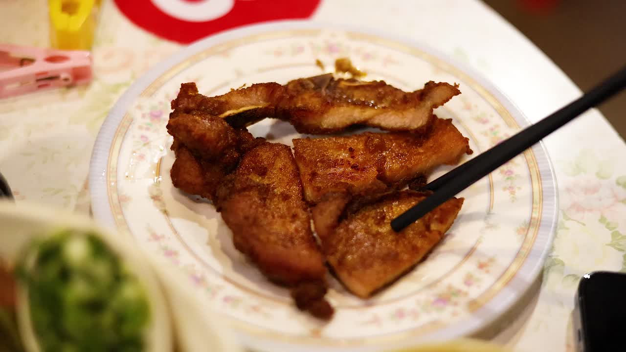 Chopsticks picking fried pork from a plate