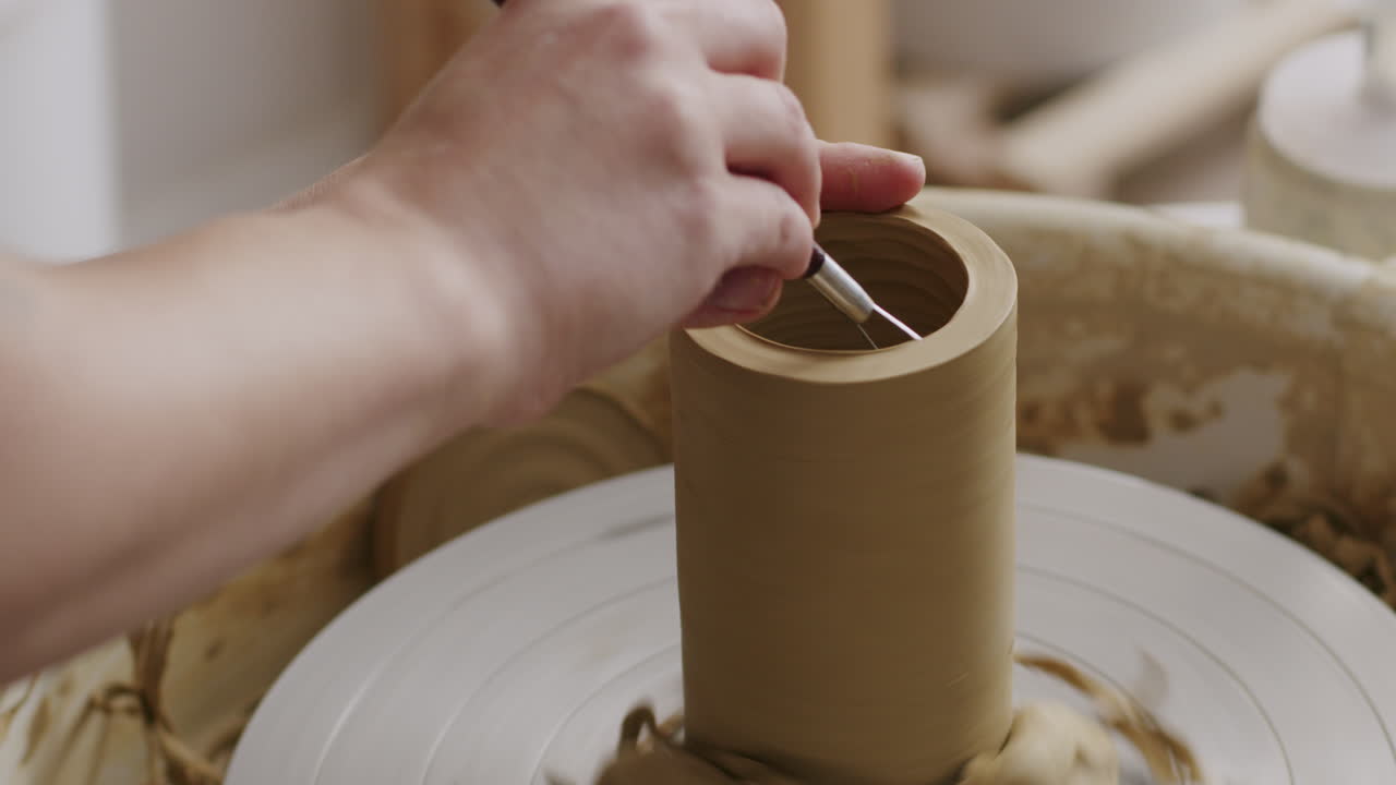 крупный план рук, формирующих глину на керамическом колесе