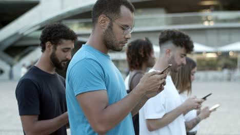 hombre afroamericano enfocado usando un teléfono inteligente