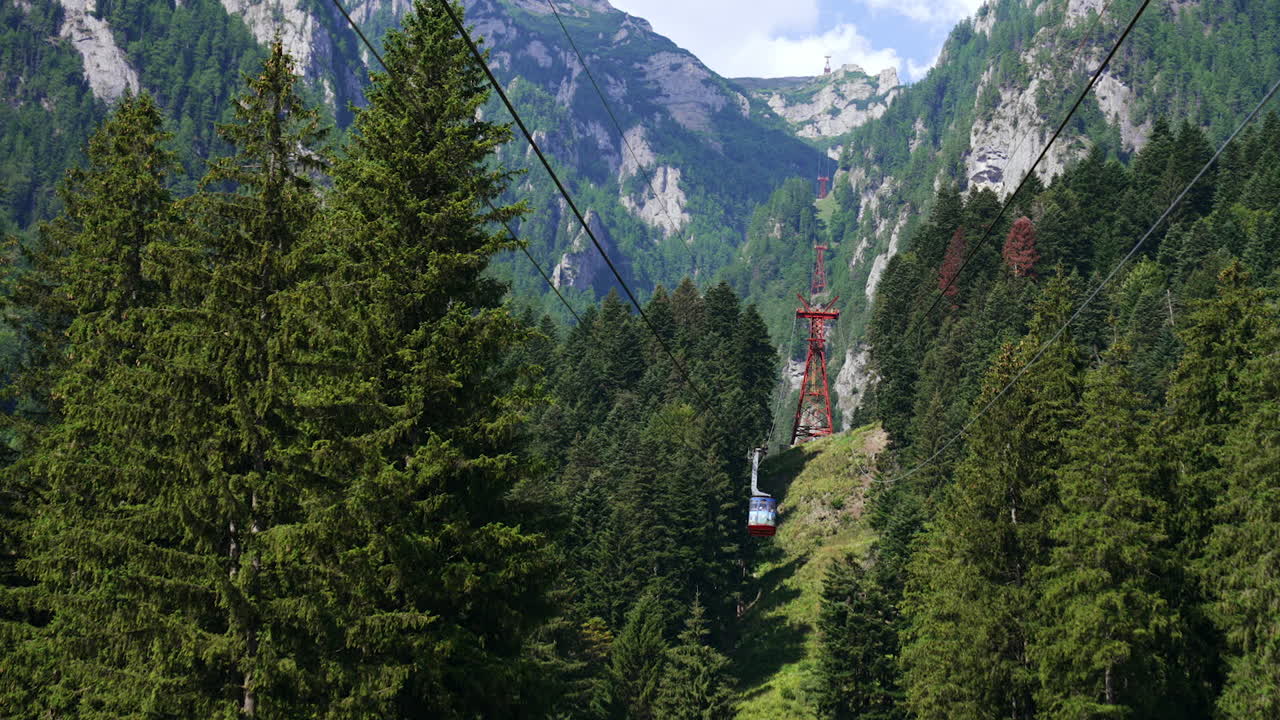 Mountain cable car scenery. Travelers enjoy a cable car ride amidst dense forests and towering mountains under a clear blue sky