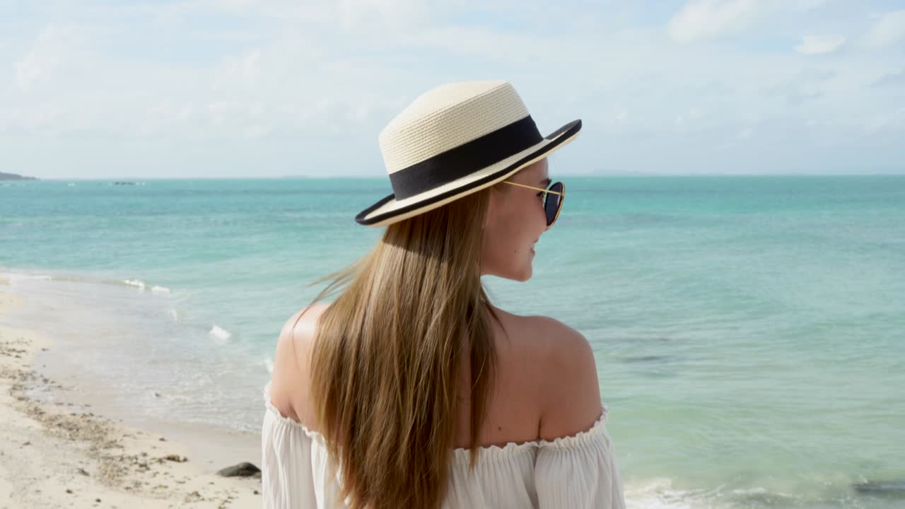 woman walks on the old wood bridge seaside wearing a sea hat.