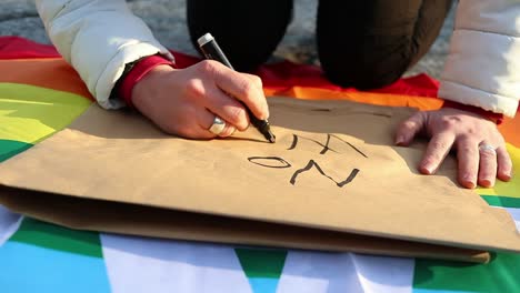 female caucasian hand writes anti-war protest placard, slow motion close up shot