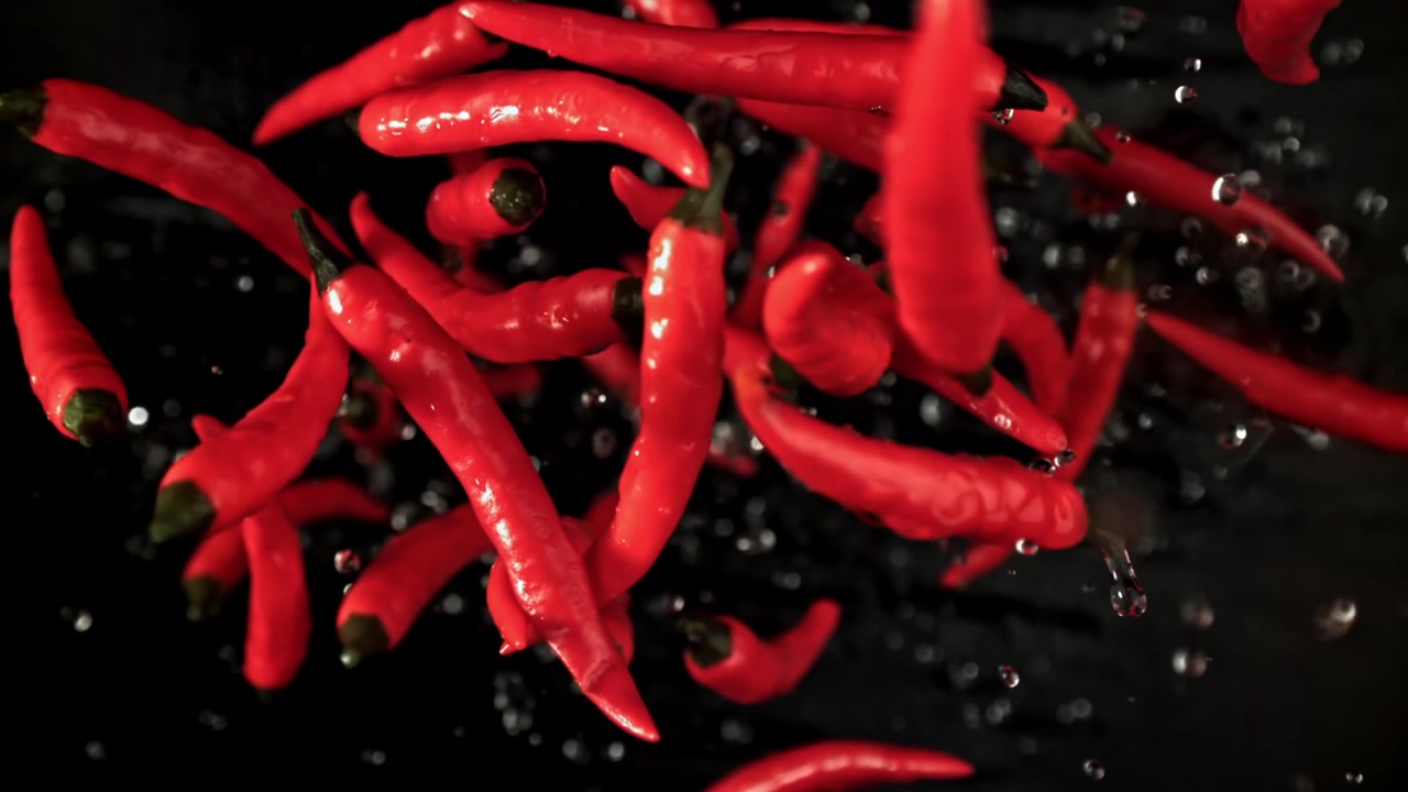 Fresh Red Chili Peppers Splashing into Water in Slow Motion