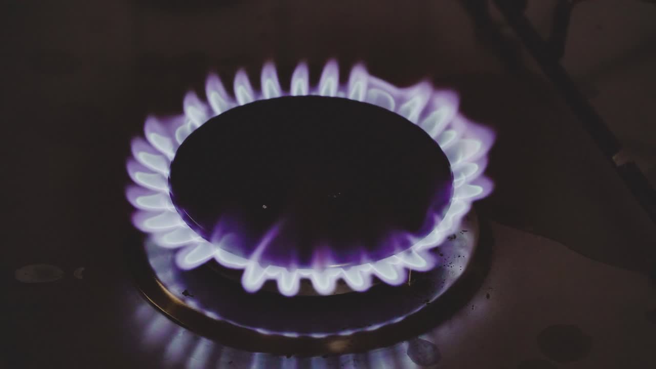 가스가 켜지고, 파란 불꽃이 불고 있습니다. 검은 바탕에 가스 스토브