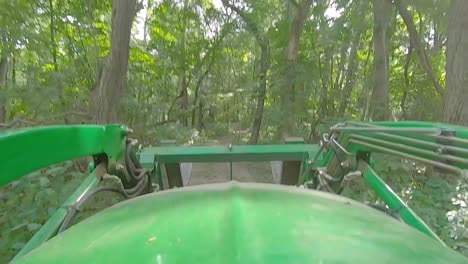 POV-Des-Maschinenbedieners,-Der-An-Einem-Sonnigen-Tag-Auf-Einem-Weg-Durch-Den-Wald-Einen-Lader-Mit-Gabeln-Fährt