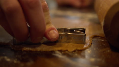 male hand cutting the flattened gingerbread dough with cutting form