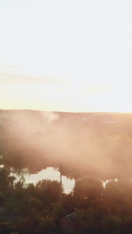 smoke are enveloping a river as a result of a fire after a drought on the background of power station into the distance. aerial view vertical video