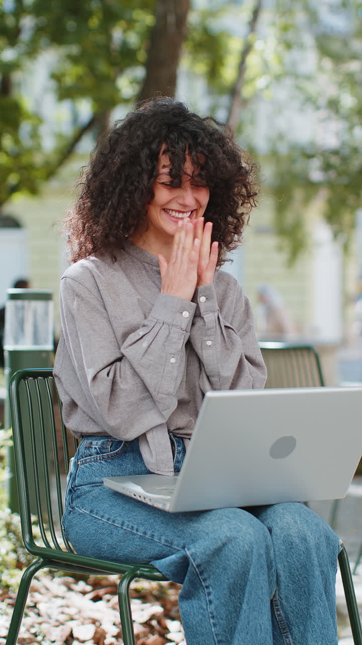 mujer blanca feliz trabajando en una computadora portátil celebrar el éxito ganar dinero sentado en la calle urbana en la ciudad