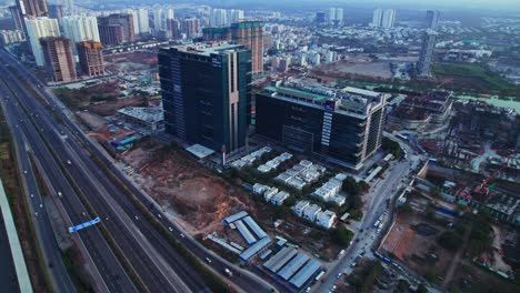 gar infobahn buildings with hyderabad orr and vehicles at nanakramguda, financial district, hyderabad, telangana, india. day time, moving up, tilt down, drone shot, 4k.