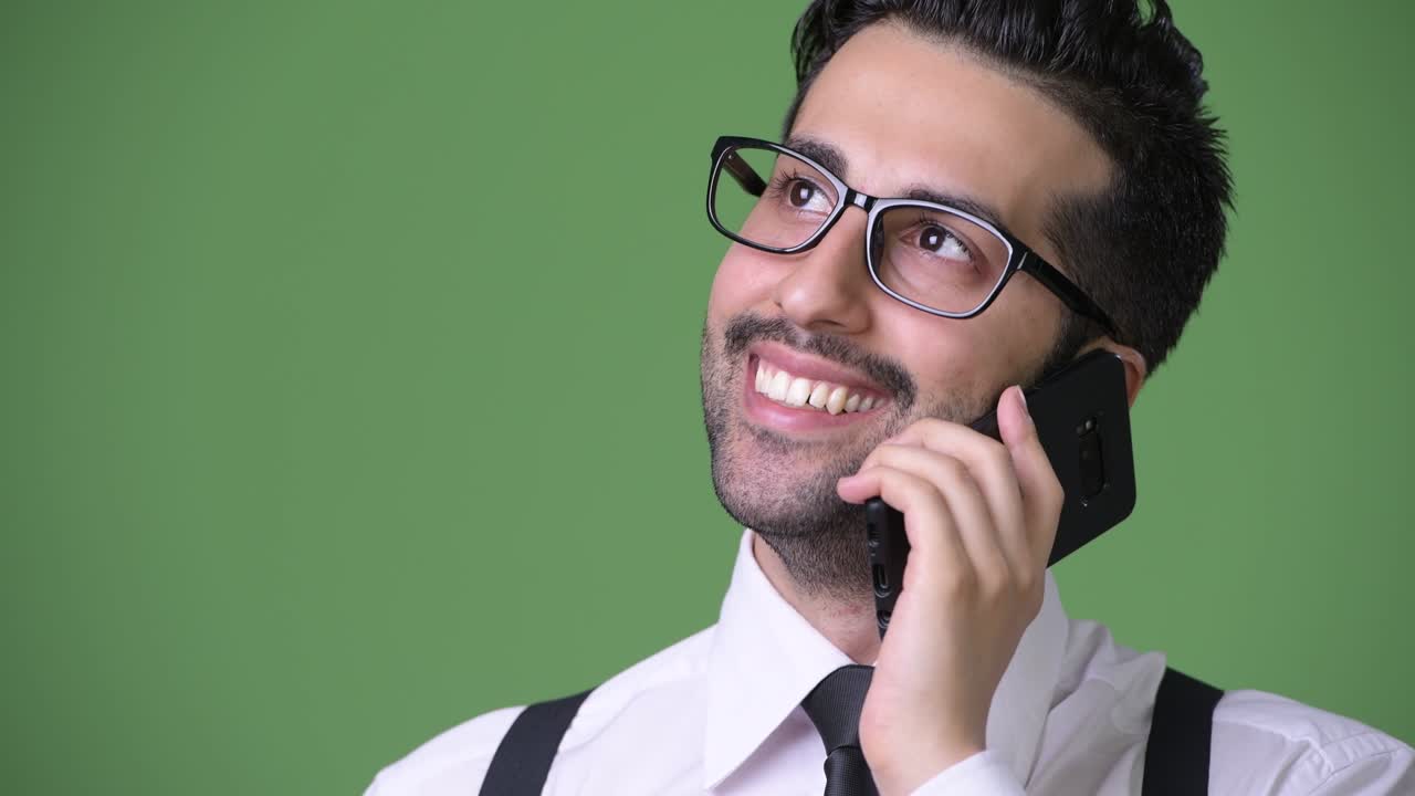 joven empresario persa barbudo y guapo contra un fondo verde