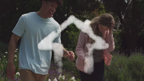 animation of cloud house over happy diverse couple dancing and holding hands in garden