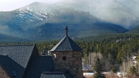 simple elegant cross on top of old chapel in rocky mountains of allenspark colorado, telephoto parallax