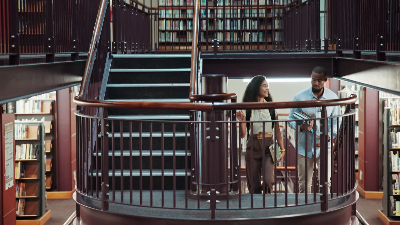 Two Diverse Students Talking and Walking Up Stairs in a University Library