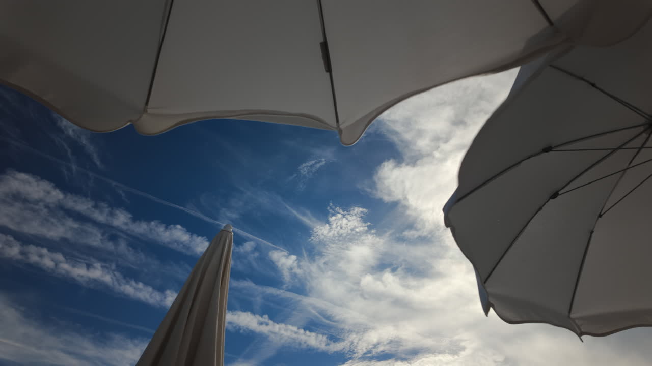 Sunny seaside view with white beach umbrellas framing a bright blue sky and calm sea