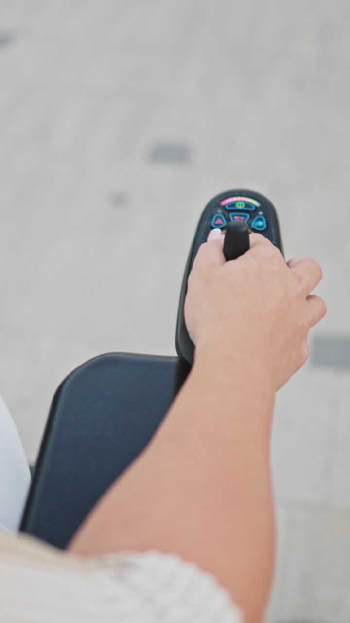 Primo piano di una mano che aziona il joystick su una sedia a rotelle elettrica