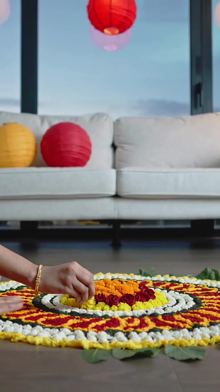 Video vertical: Manos de mujer con brazalete de oro colocando caléndulas y formando un rangoli en casa para la puja.