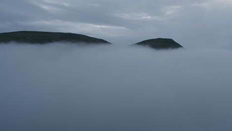 the camera emerges from the thick clouds, a view of a mountain peak