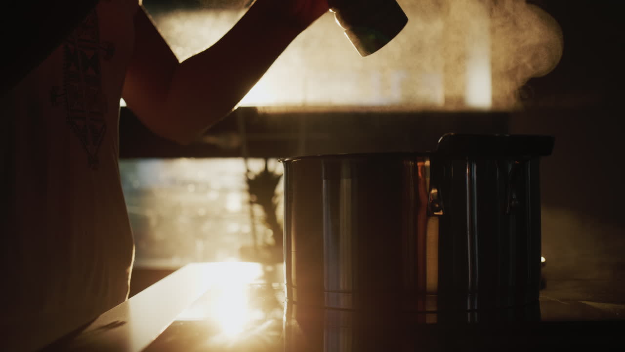 여자 는 스토브 에 조리 되고 있는 수프 에 고추 를 뿌린다