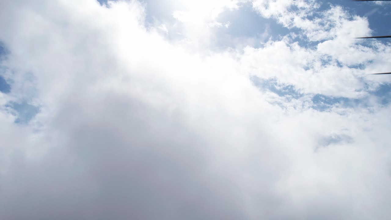 Droneoptagelse fra luften af sol og skyklædte bjerge.