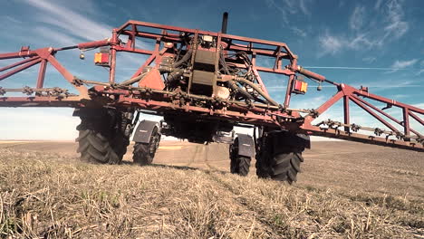 tractor agrícola de trabajo en tierras de cultivo rociando herbicidas durante un día soleado