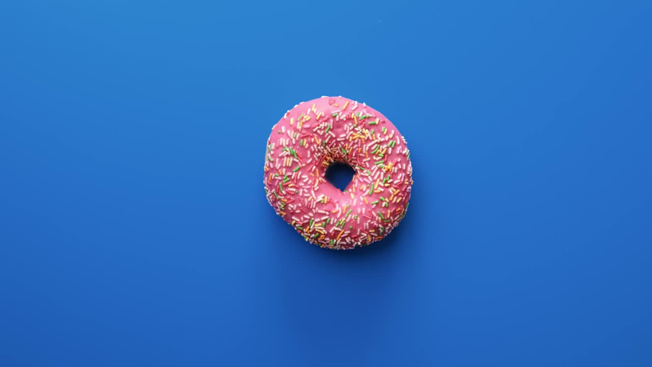 Ciambella dolce e luminosa che ruota lentamente con glassa colorata al cioccolato, isolata su blu