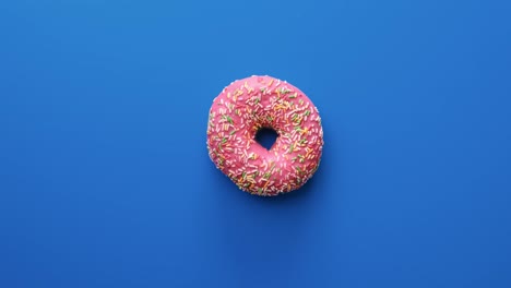 girando lentamente de dulce rosquilla brillante con colorido helado chocolate aislado en azul