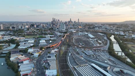 establishing pull away ascending drone shot of brisbane city, shot during sunset, flying over the inner city bypass icb road network