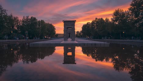 Front-symmetrical-view-timelapse-of-Templo-de-Debod-temple-during-colorful-and-beautiful-clouds-and-sunset-in-Madrid-with-perfect-reflection-park