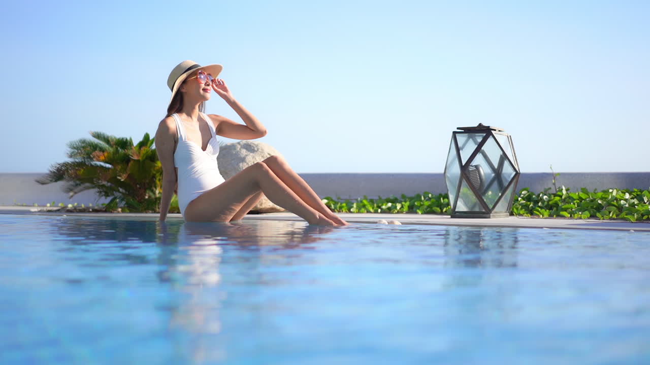 chica joven atractiva disfrutando de la puesta de sol junto a la piscina en cámara lenta de ángulo bajo