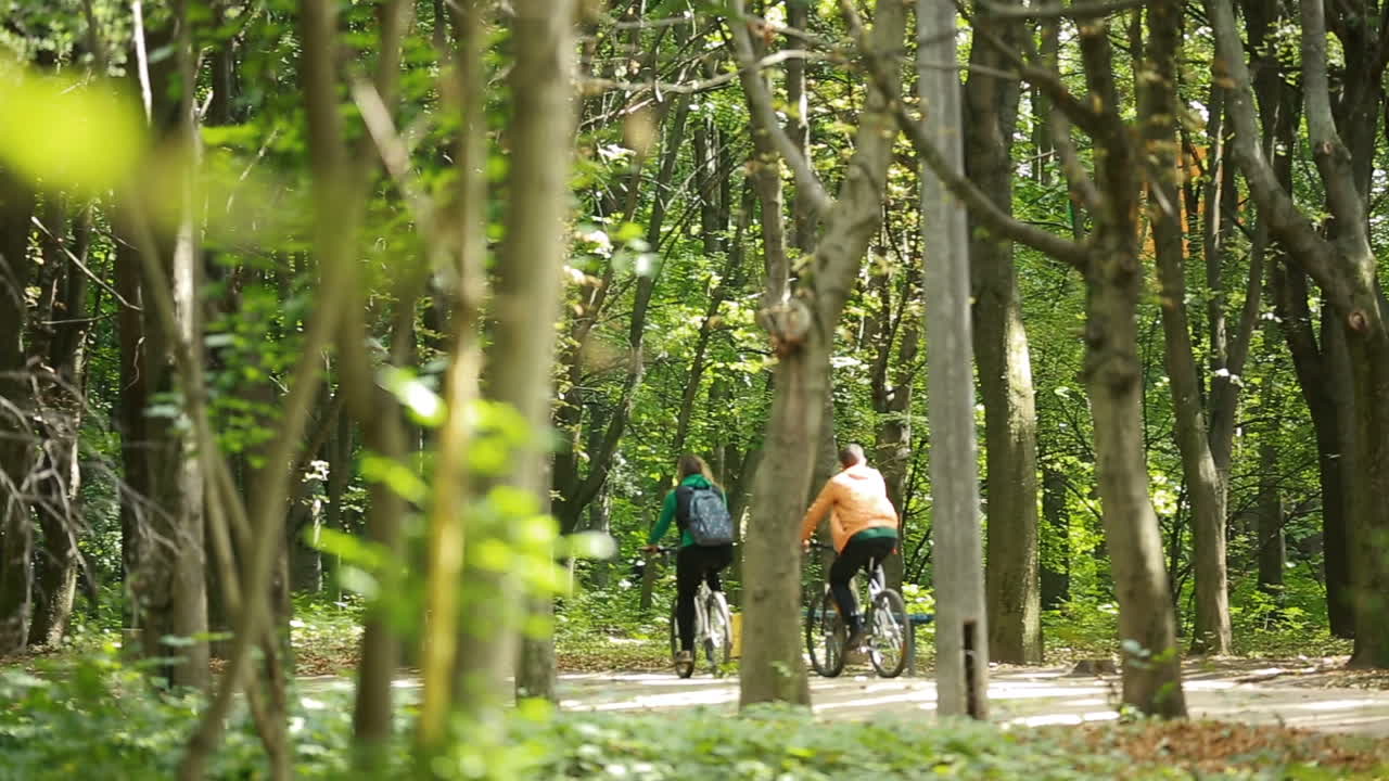 Couple In Love Ride Bicycles. Happy funny young couple riding on bicycle in nature