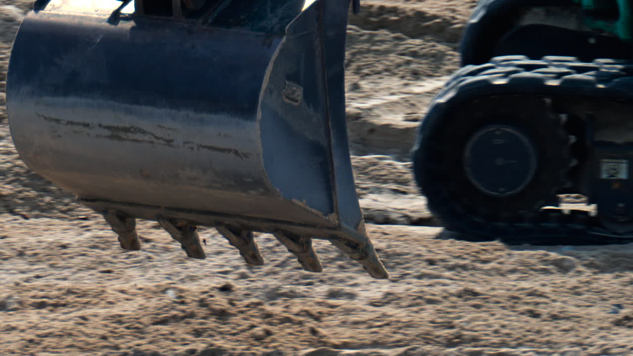 Close up of the wheels of an yellow loader spreading sand on the beach