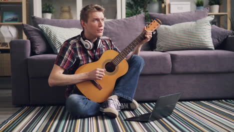 young man learning guitar online