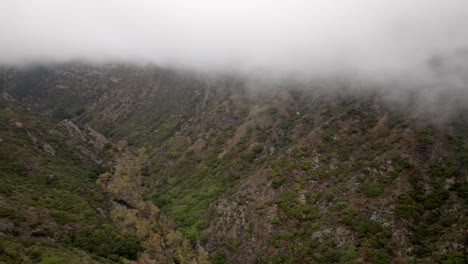 Santa-Monica-Mountains-in-Malibu,-California-with-traffic-driving-on-road-and-drone-video-panning-left-to-right