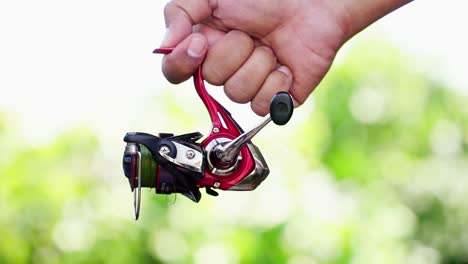 the hand holding the spinning fishing reel enters the video frame