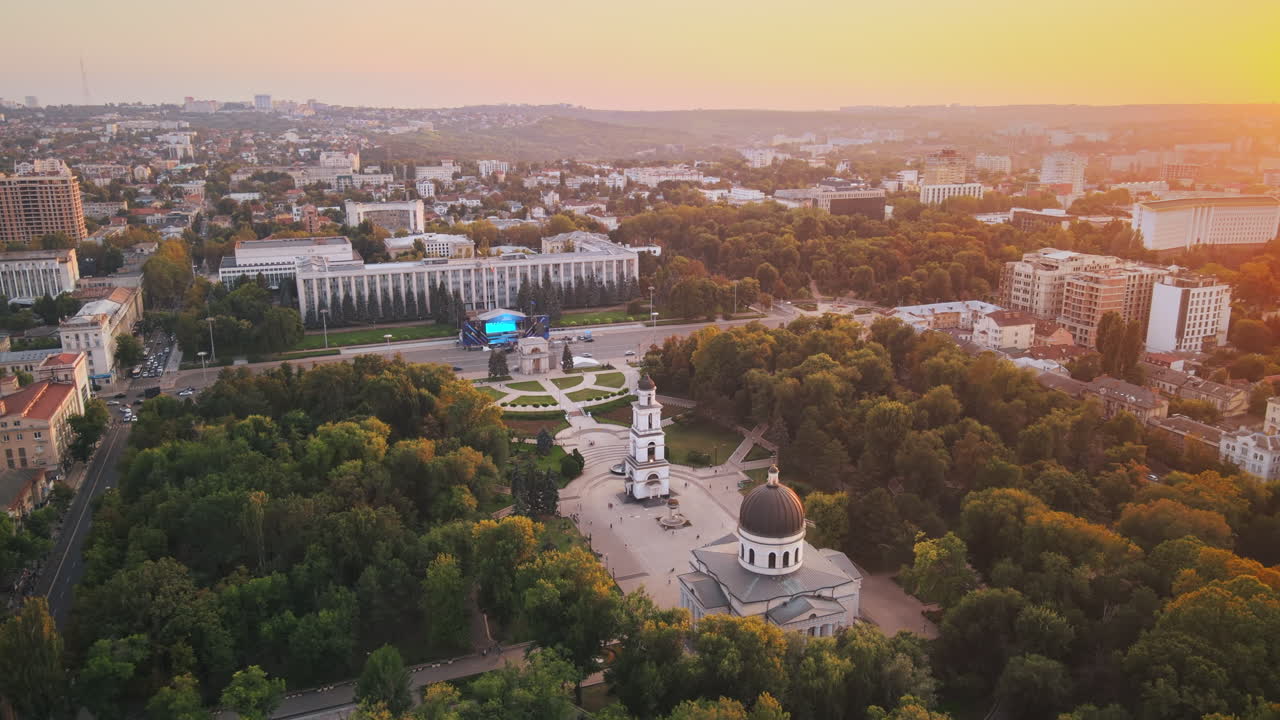 Aerial drone view of Chisinau downtown at sunset. Panorama view of multiple buildings, central park, roads with moving cars. Moldova