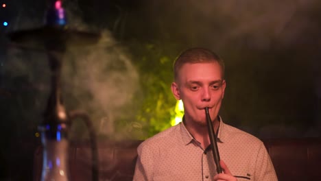 man smoking hookah at a night club