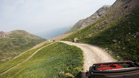 view of the sunroof of 4wd vehicle traversing along a narrow trail across very steep alpine meadow near black bear pass in san juan mountains of colorado