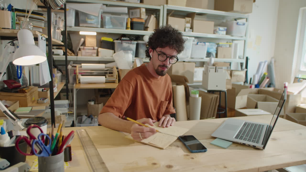 Man Web Calling and Taking Notes at Work in Delivery Service Office