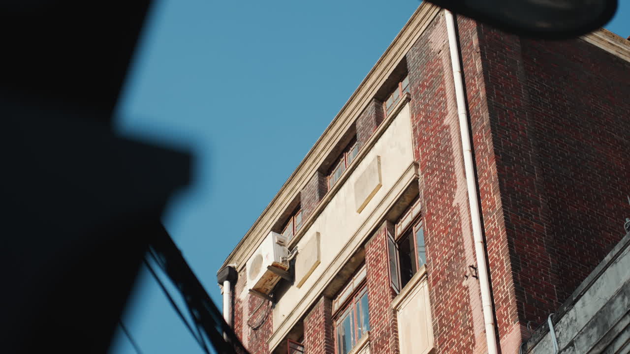 Angolo di edificio in mattoni sotto un cielo azzurro brillante, primo piano su muratura stagionata e cornice ornata, fotografo urbano cattura texture e ombra mentre un architetto ispeziona i dettagli strutturali, fuoco vintage