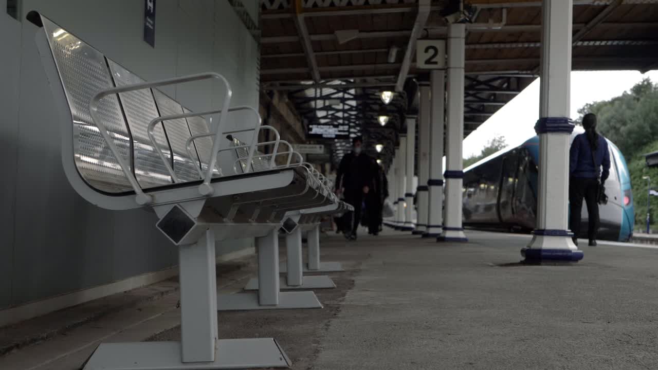 Passengers leaving train station platform low wide shot